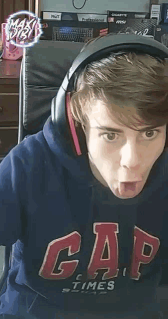 a young man wearing headphones and a gap hoodie is sticking out his tongue .