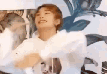 a woman in a white shirt is dancing in front of a wall with flowers on it .