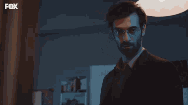 a man with glasses and a beard is standing in front of a fox logo