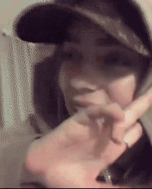 a blurry picture of a person wearing a hat covering their mouth