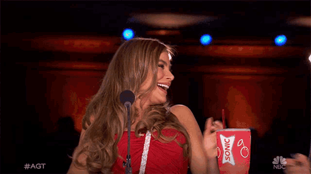 a woman in a red dress is holding a cup that says sonic