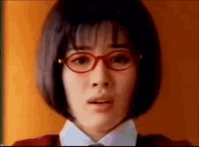 a close up of a woman wearing glasses and a red shirt .