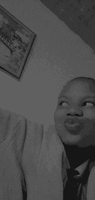 a black and white photo of a young boy making a funny face .