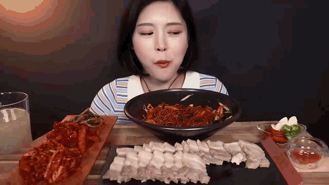 a woman is sitting at a table eating a bowl of noodles