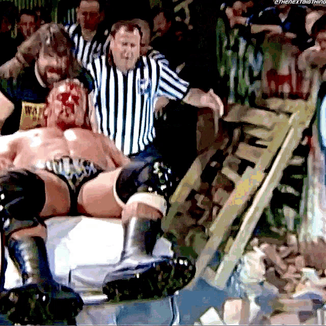 a wrestler is laying on the ground with a referee and a sign that says the next time