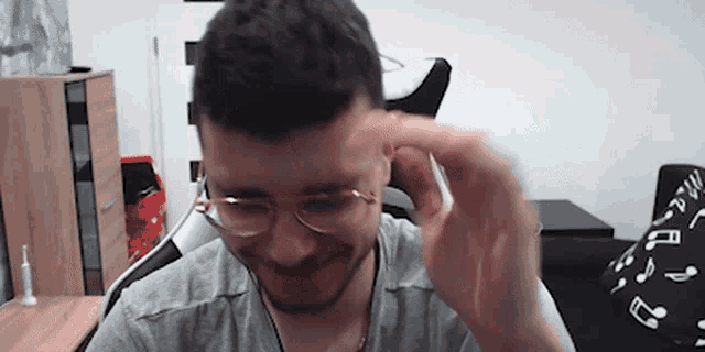 a man wearing glasses and a grey shirt is sitting in a chair