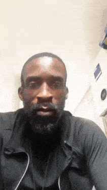a man with a beard is wearing a black jacket and a black shirt