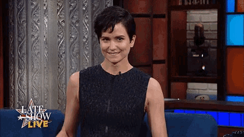 a woman is sitting on a couch in front of a late show live sign