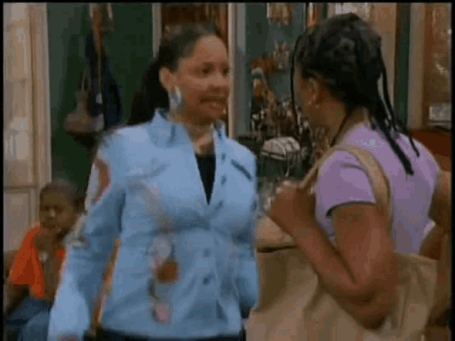 two women are standing next to each other in a room and talking .