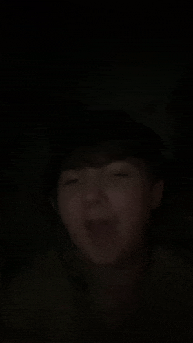 a person is making a funny face in the dark .