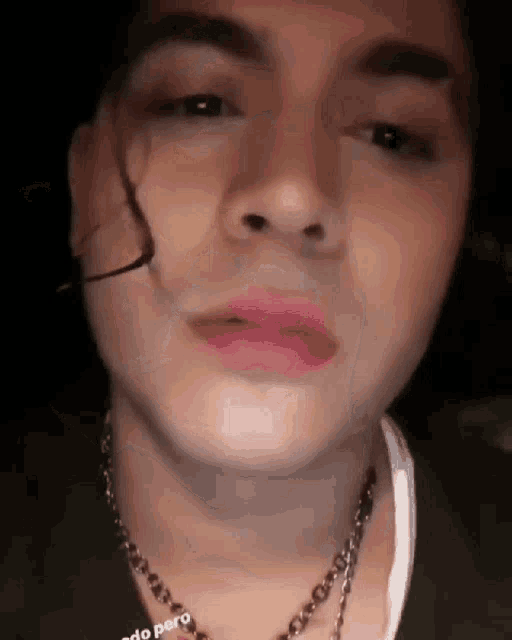 a close up of a person 's face with a necklace and pink lipstick .