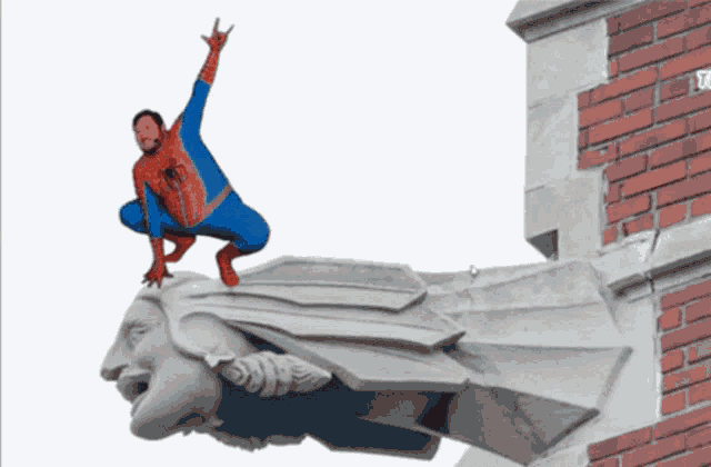 a man in a spiderman costume is kneeling on a gargoyle