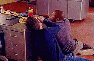 two men are kneeling on the floor eating pizza
