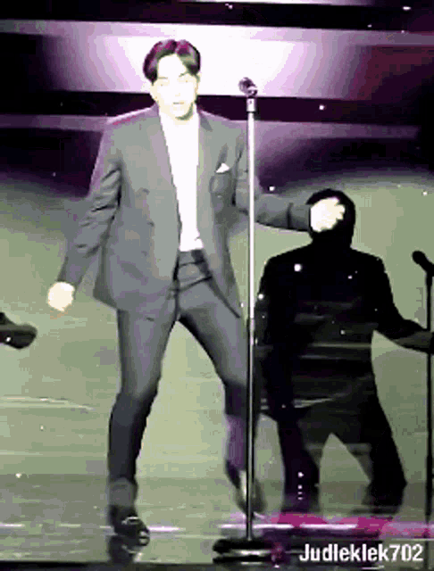a man in a suit is dancing in front of a microphone with judleklek702 written on the bottom right