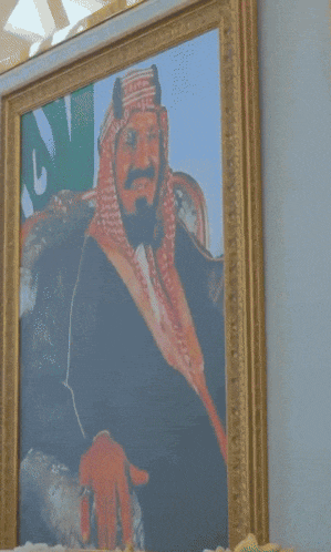 a man sitting in front of a painting of a man with a beard