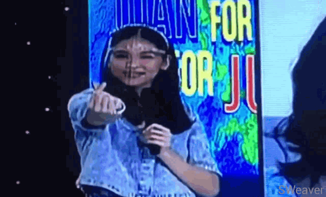 a woman is giving a thumbs up in front of a sign that says " i want for you "