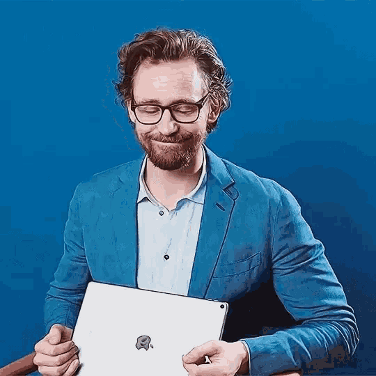 a man in a blue suit and glasses is holding a tablet computer .
