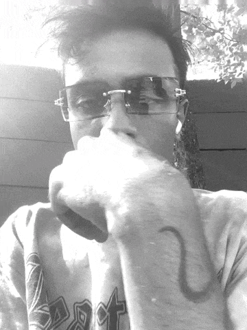 a black and white photo of a man wearing sunglasses and a shirt with the letter t on it