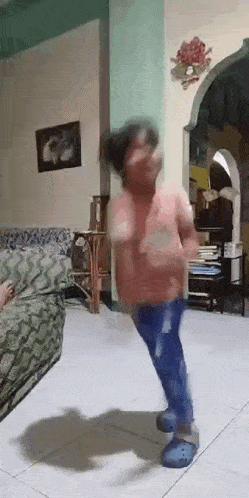a person is dancing in a living room with a couch in the background .
