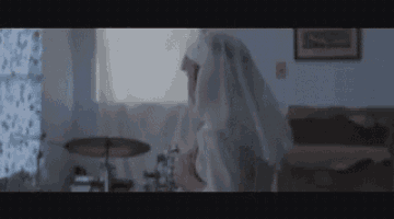 a nun is playing drums in a bedroom with a drum set .