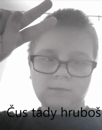 a black and white photo of a boy wearing glasses and the words cus tady hrubos below him