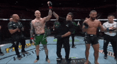 a referee holds up a fighter 's hand in a boxing ring