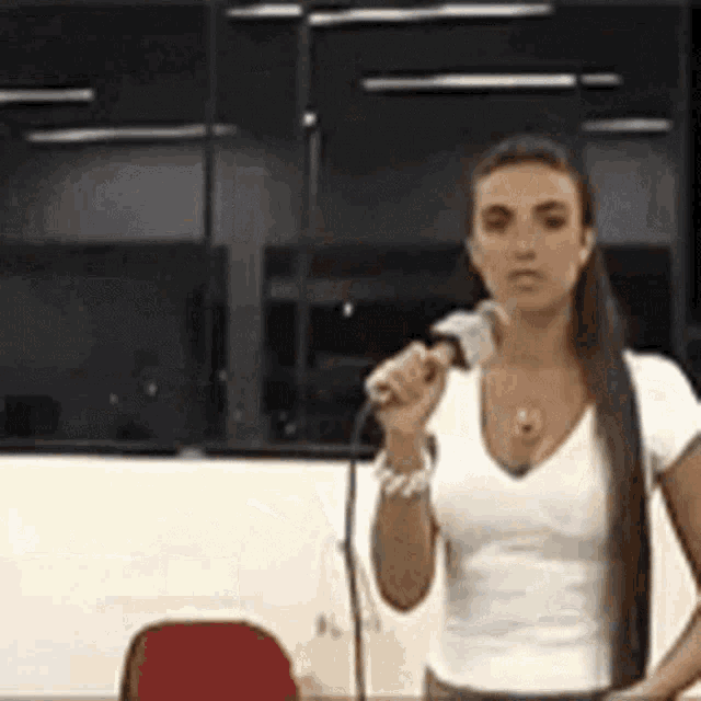 a woman in a white shirt is holding a microphone in her hand .