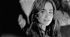 a black and white photo of a woman looking at the camera .