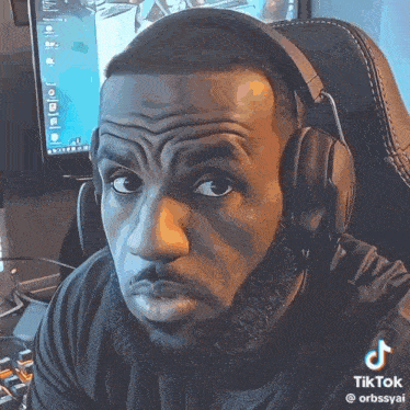 a man wearing headphones is making a funny face in front of a computer monitor