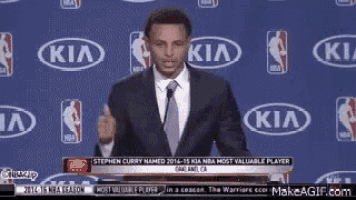 a man in a suit and tie is standing in front of a kia logo