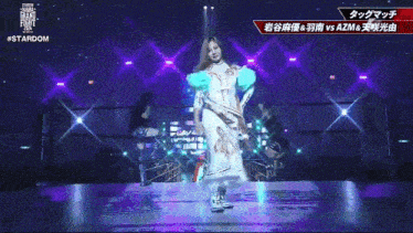 a woman in a white dress is dancing on a stage with purple lights and the words stardom on the bottom