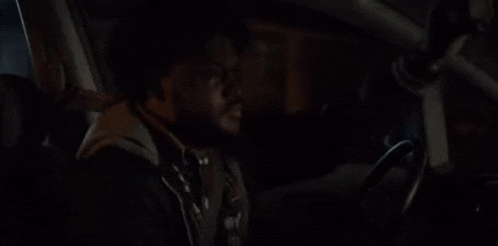 a man is talking on a cell phone while sitting in a car at night .