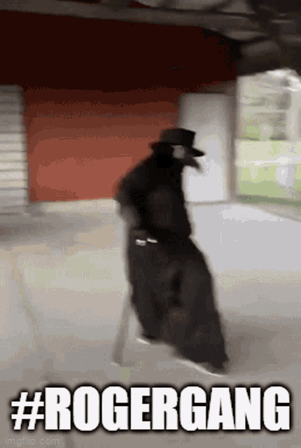 a man in a black coat and hat is walking down a sidewalk with the words `` rogergang '' above him .
