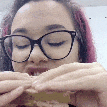 a woman wearing glasses and a nose ring is eating something