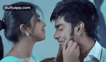 a woman is touching a man 's face while they kiss .