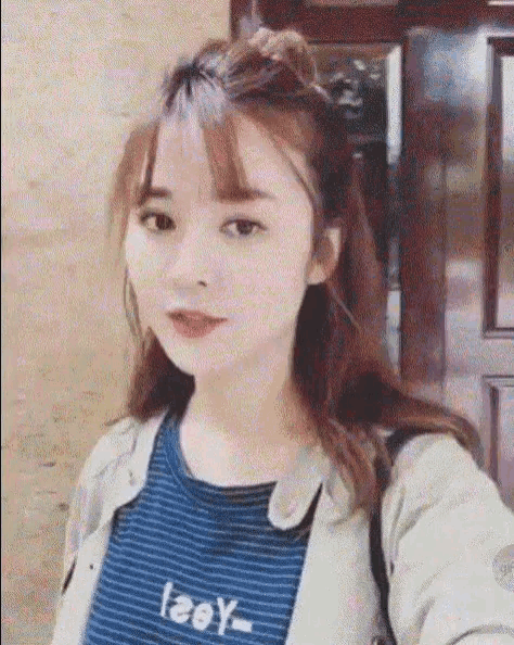 a young woman is taking a selfie with her phone while wearing a striped shirt that says leey
