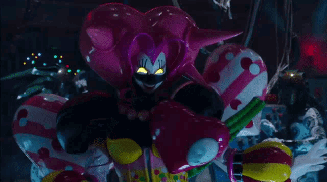 a pink and yellow clown with glowing eyes is surrounded by pink and yellow balloons