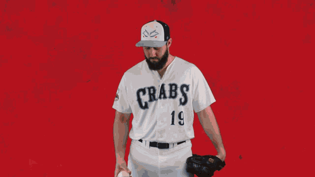 a man wearing a crabs jersey throws a baseball