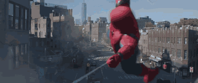 a person in a spiderman costume is flying over a city street with a sign that says high school