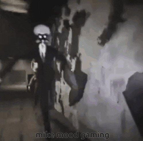 a man in a suit and tie is standing in a dark room with the words `` mike mood gaming '' written below him .