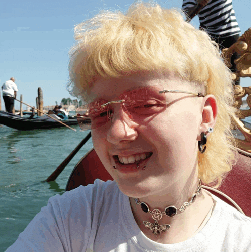a woman wearing sunglasses and a necklace with a pentagram on it smiles for the camera
