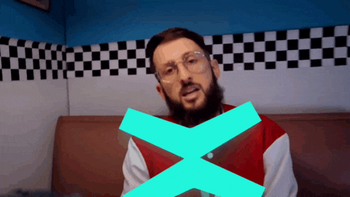 a man with glasses and a beard has a blue x on his chest