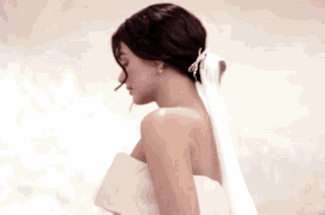 a woman in a wedding dress is standing in front of a wall .