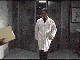 a man in a lab coat is walking through a door