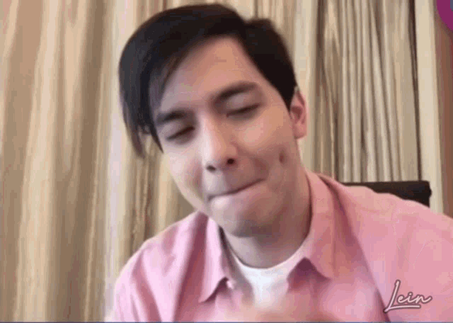 a man in a pink shirt is making a funny face with his mouth open .