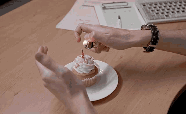 a person is lighting a cupcake with a lighter