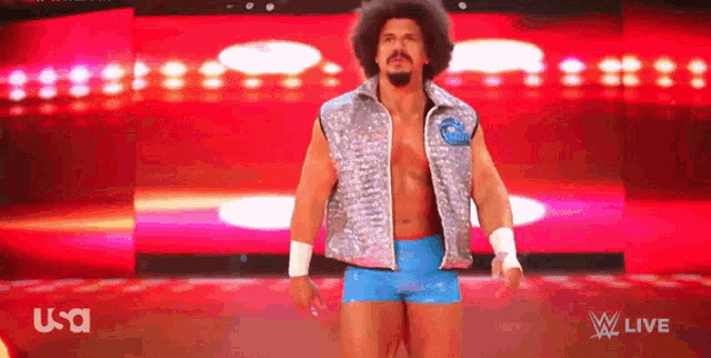 a man in a silver vest and blue shorts stands in front of a red background that says usa on it