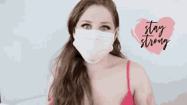 a woman wearing a pink face mask with the words stay strong written on a pink heart