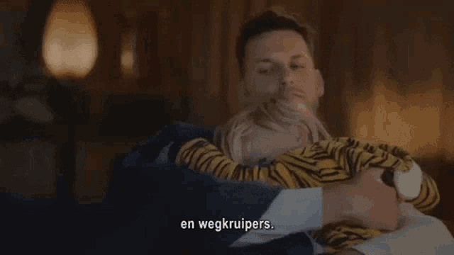 a man is holding a baby in his arms and the words en wegkruipers are visible in the corner