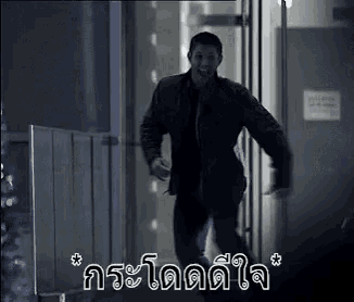 a man is running through a doorway in a dark room with a foreign language .